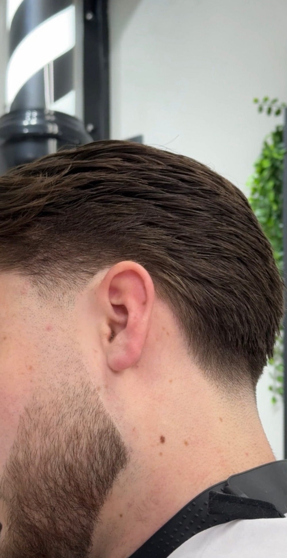 Close-up van een taper fade in de nek met een strak bijgewerkte baardlijn